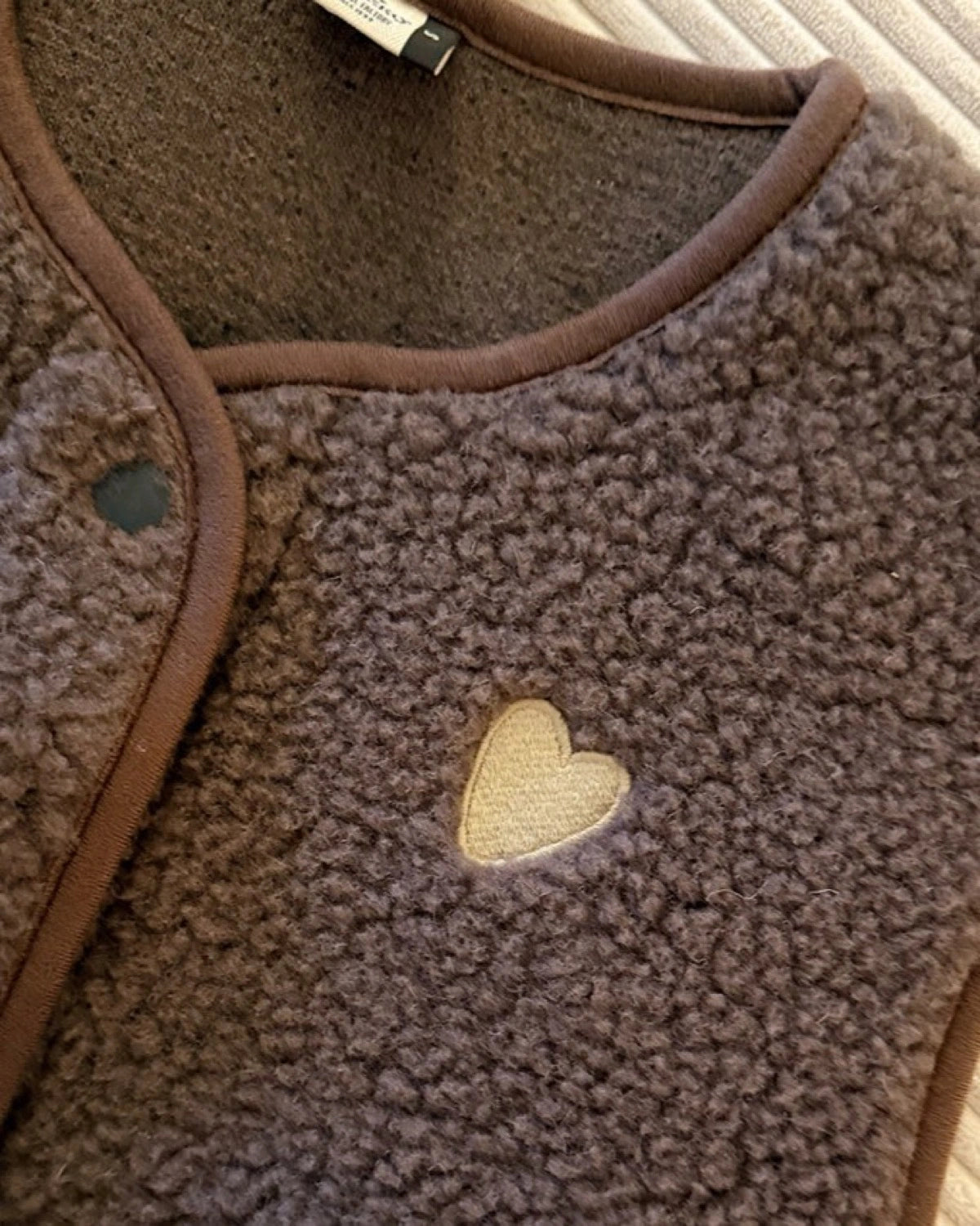 Dunkelbraune TYB Wollweste mit cremefarbenem Herz, Detail